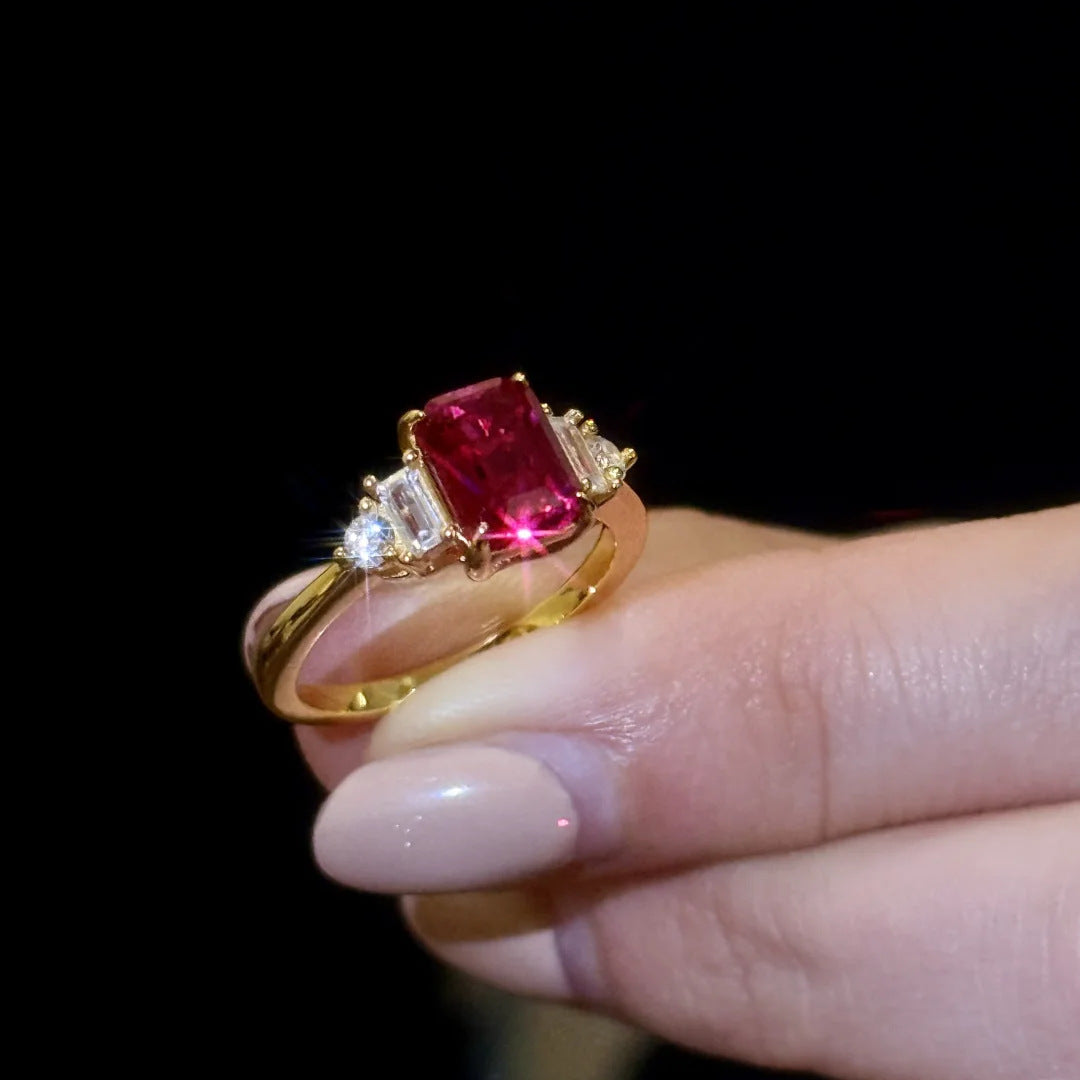 Detail shot of emerald-cut Red Gemstone Gold Ring with diamond accents, dark background