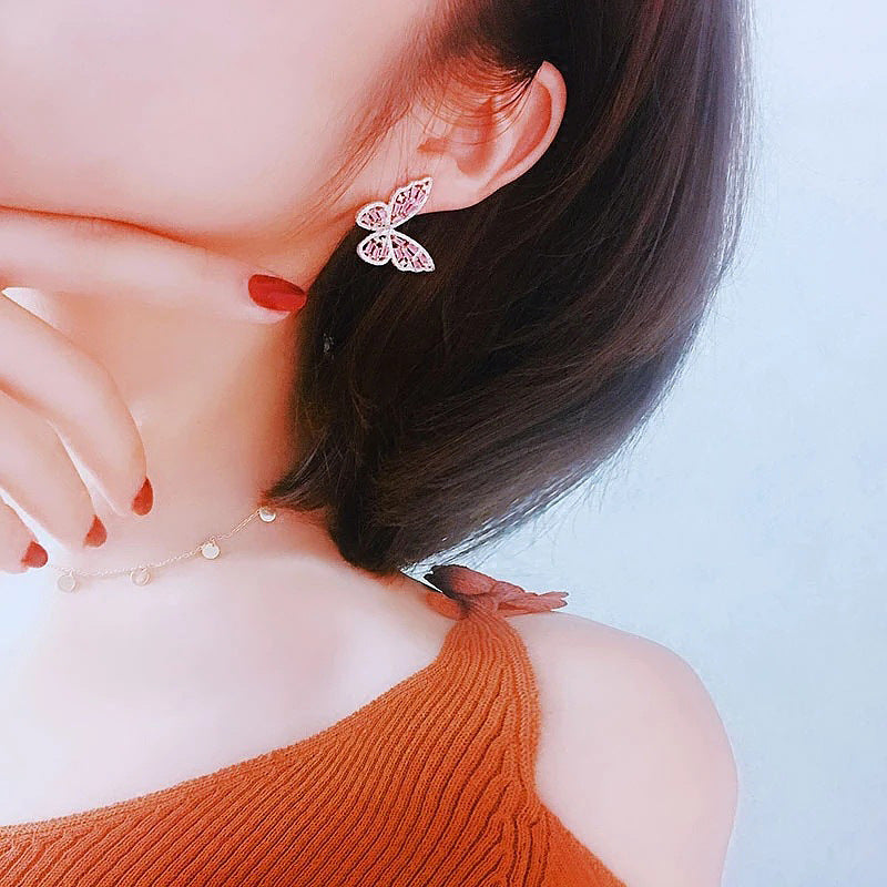 Butterfly Dangle Earrings worn by model in orange sweater, back-of-neck view showing pink crystal butterfly design