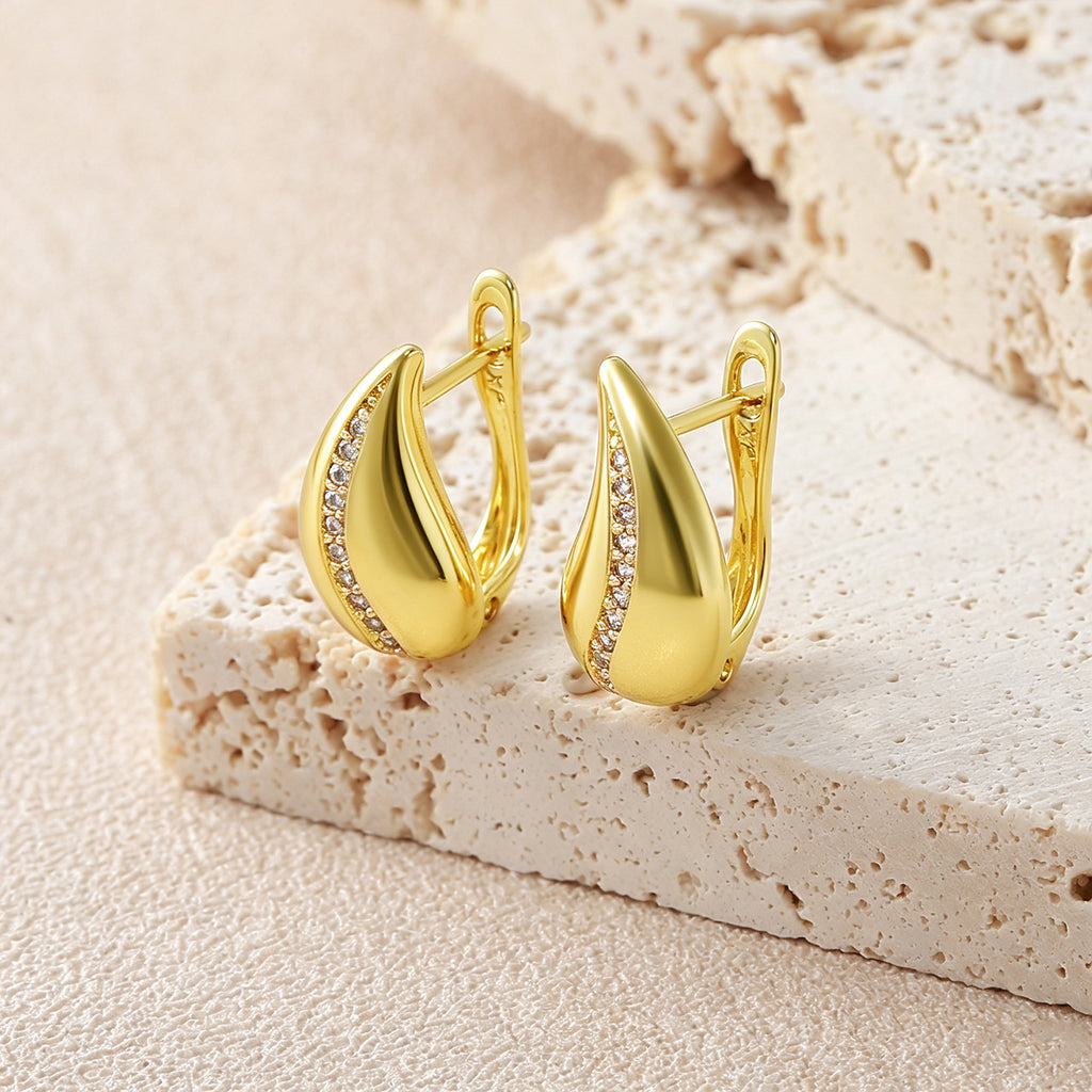 French Drop Earrings, gold teardrop hoops with pave crystal accent, standing on beige stone slab