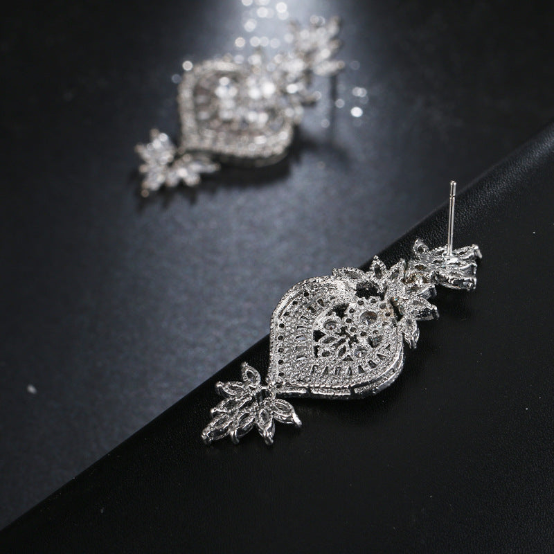 CZ Flower Drop Earrings styled loosely on dark angled surface, silver-tone cubic zirconia detail with visible earring backs