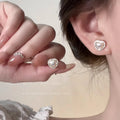 Pearl Drop Earrings worn as heart-shaped pearl stud, close-up on ear with hand holding earring