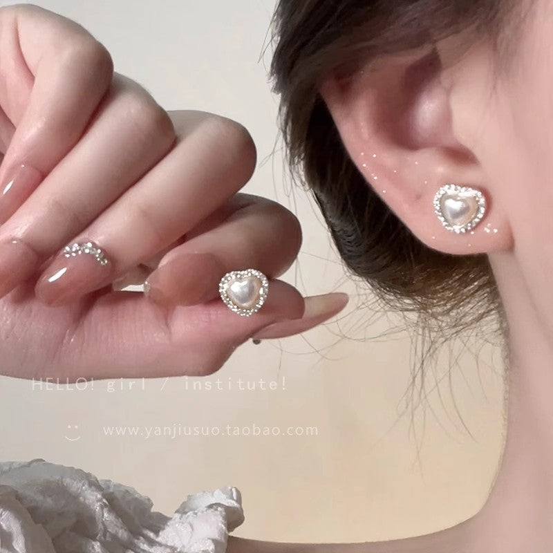 Pearl Drop Earrings worn as heart-shaped pearl stud, close-up on ear with hand holding earring
