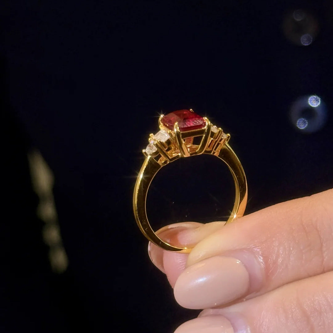 Close-up of Red Gemstone Gold Ring with diamond accents held between fingers