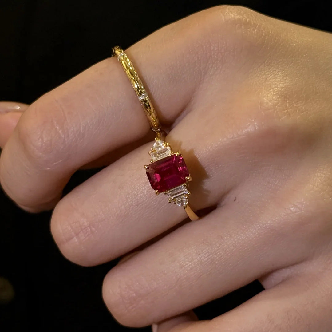 Close-up of emerald-cut Red Gemstone Gold Ring worn on finger, showing baguette diamond setting