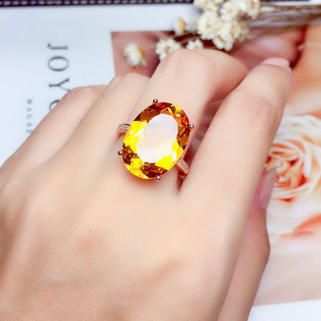Large oval citrine ring worn on hand, resting on floral background