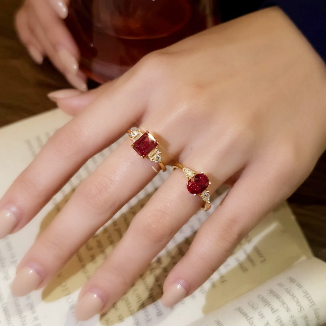 Red Gemstone Gold Rings worn on hand, resting on an open book