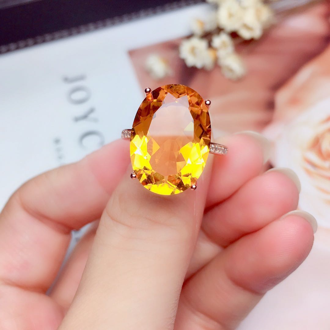 Close-up of large oval citrine ring from the Crystal Pendant Necklace Set, held between fingers