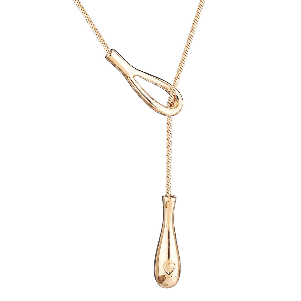 Close-up of gold-tone teardrop knot pendant on the lariat necklace, white background