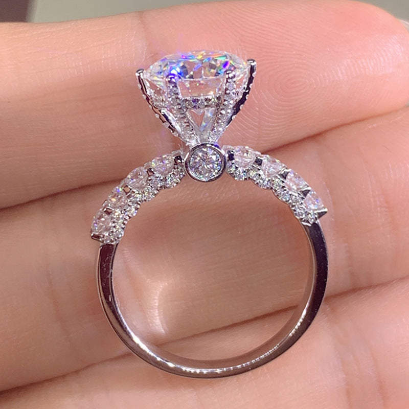 Close-up of the six-prong setting on the Six-Prong Moissanite Ring, held between fingers