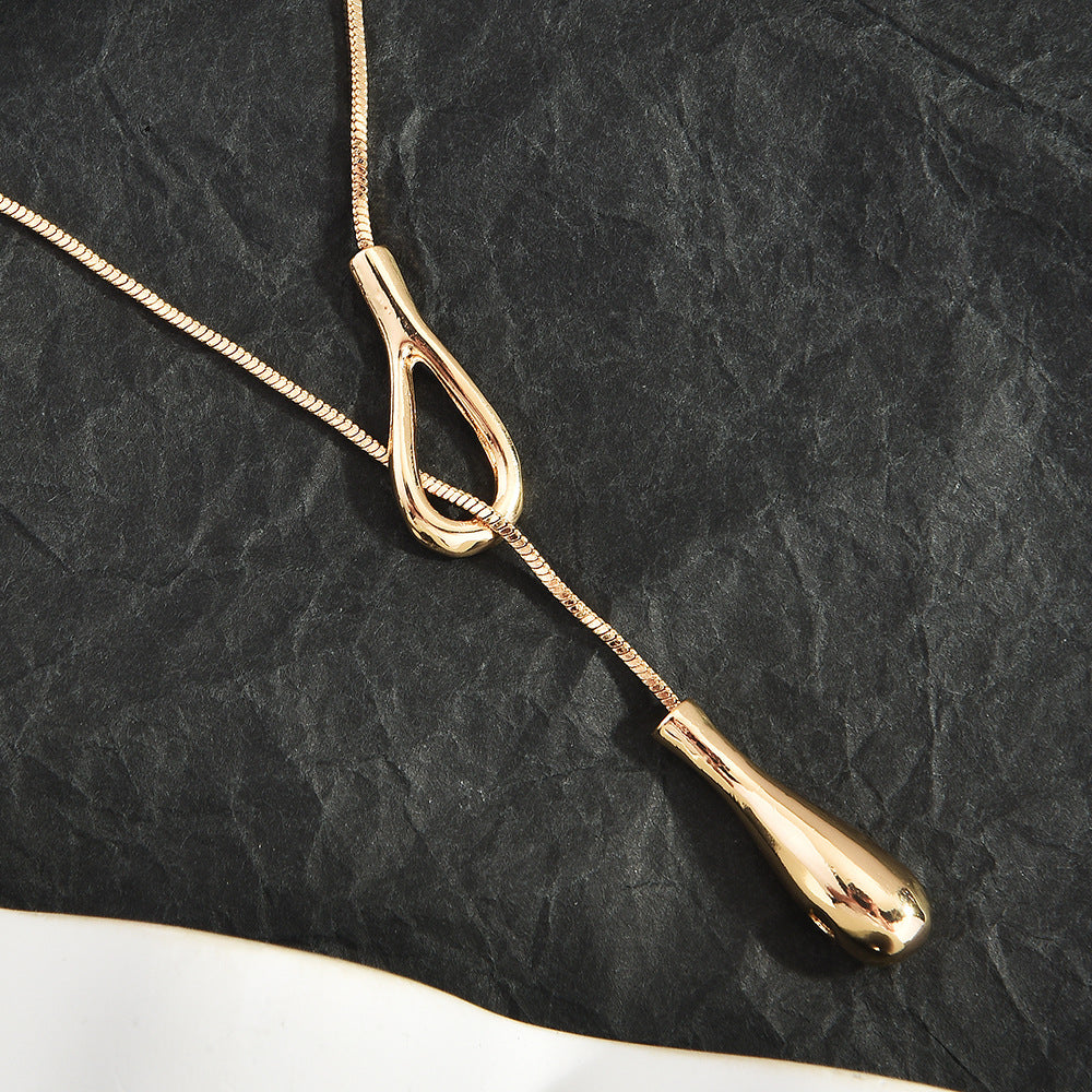 Gold Lariat Snake Chain Necklace flat lay on dark textured background