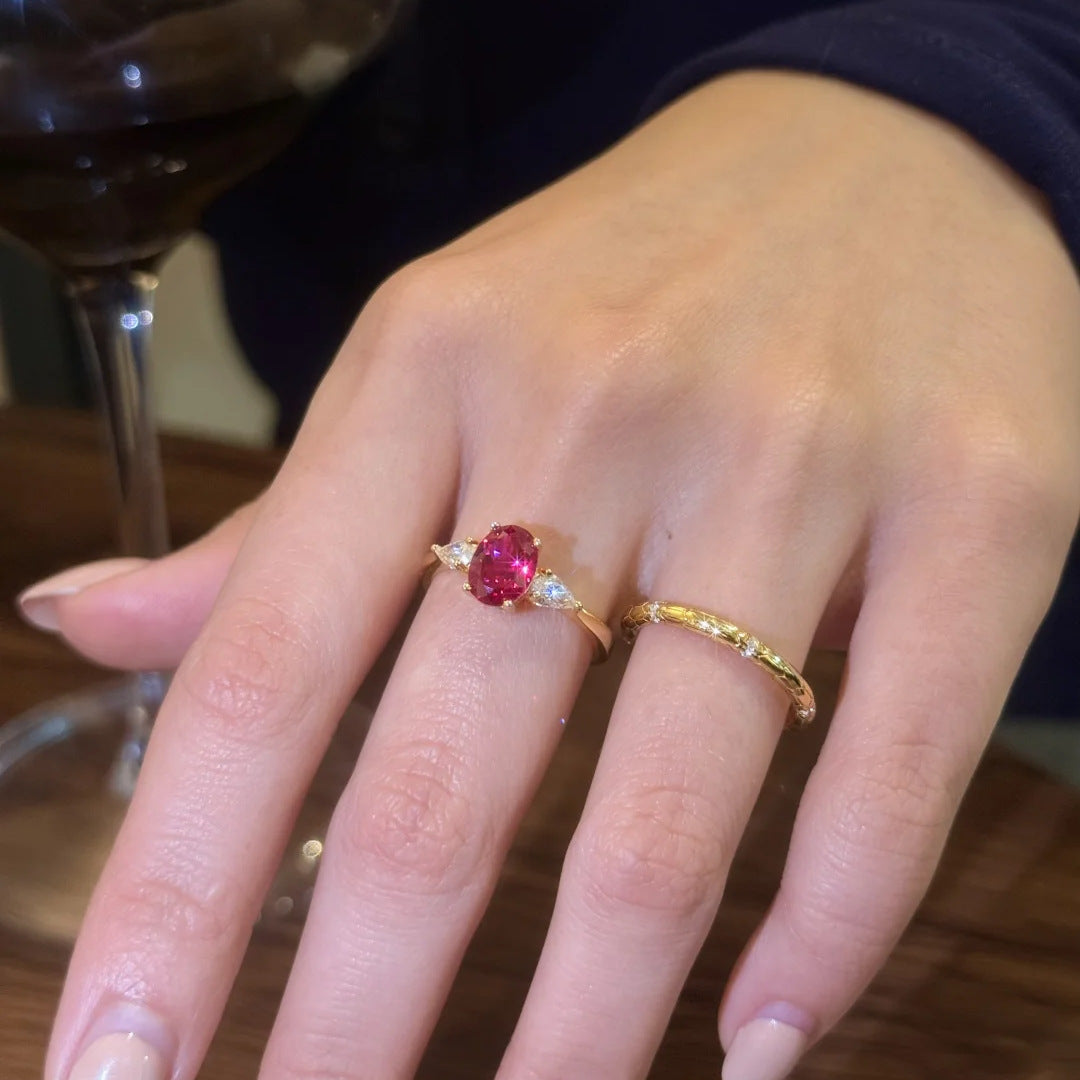 Oval-cut Red Gemstone Gold Ring stacked with a plain gold band, worn on hand