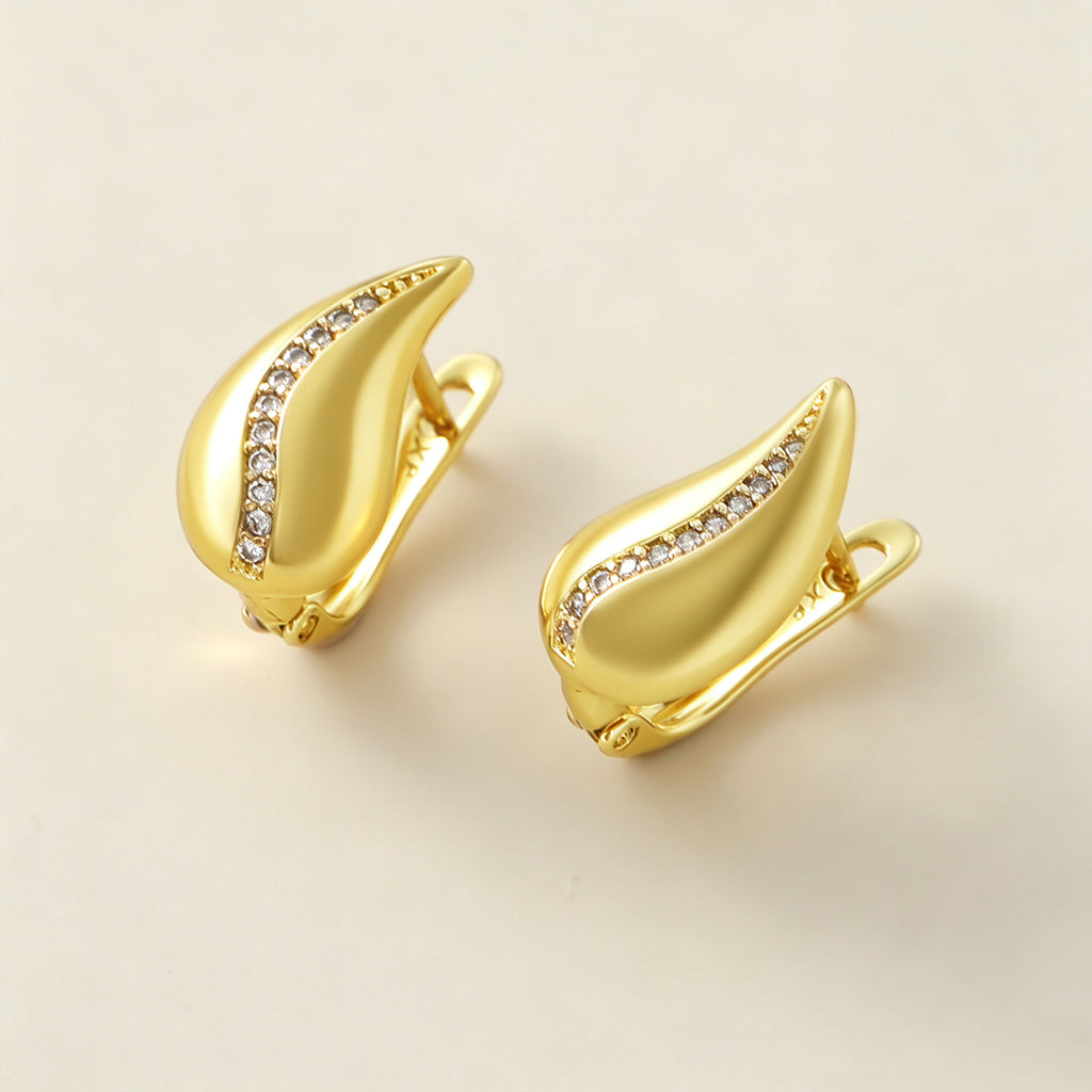 French Drop Earrings laid flat on cream background, sculpted gold flame shape with pave crystal strip