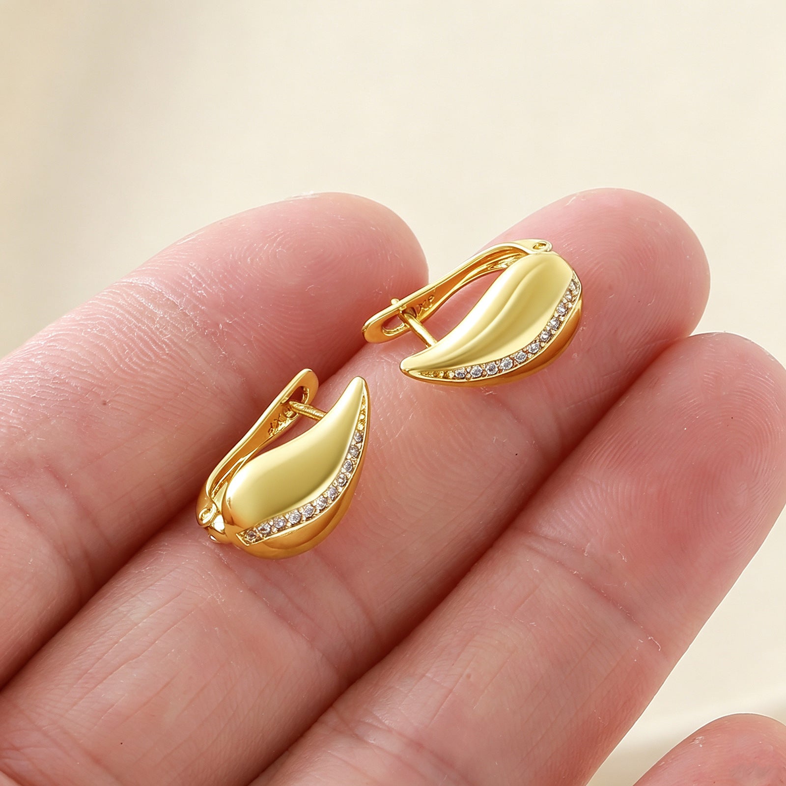 French Drop Earrings held in open palm for size reference, gold teardrop hoops with crystal accent