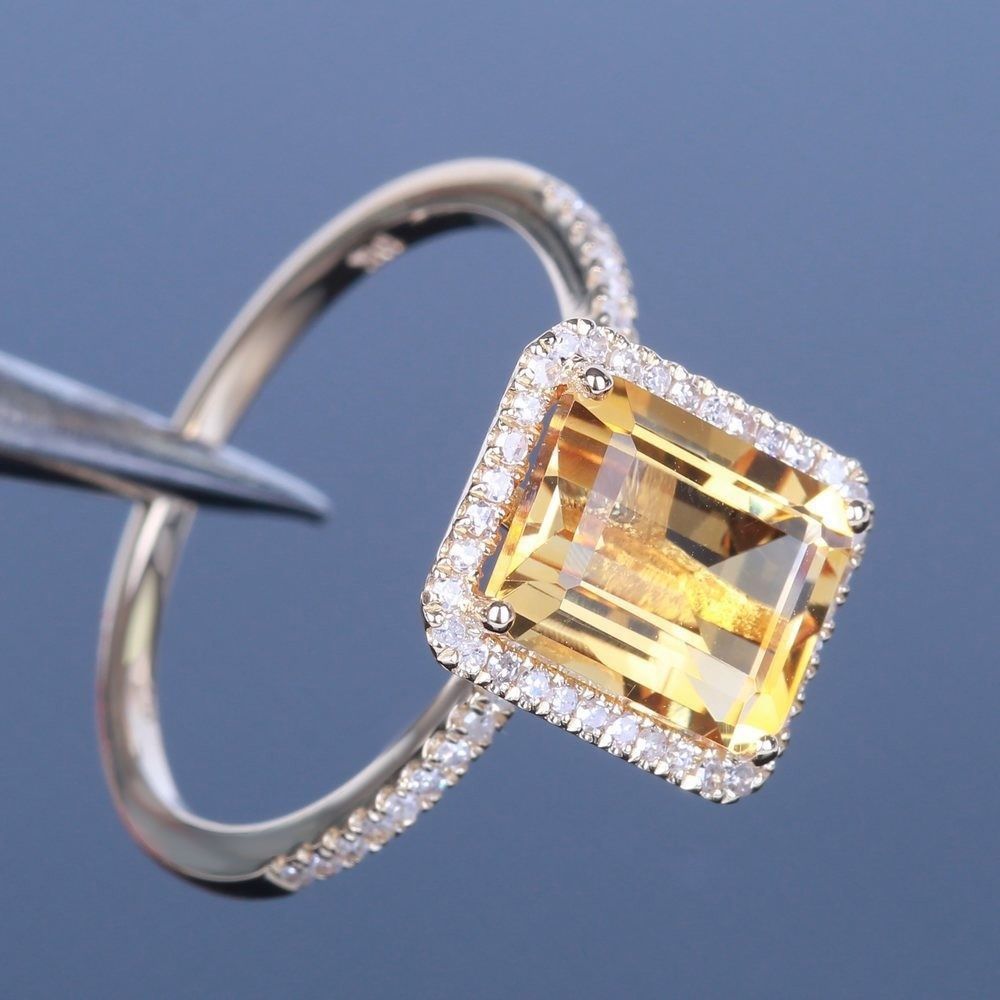 Champagne Gemstone Engagement Ring held with tweezers on blue background, detailed halo view